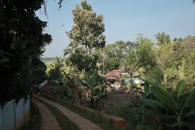 a path leading to a house with trees and a fence at Happy Land in Shoranūr