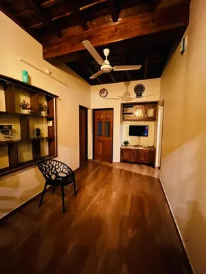 a living room with a ceiling fan and a chair at Happy Land in Shoranūr