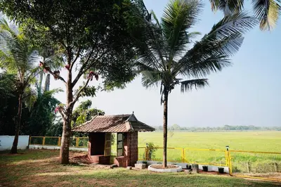 a small building in a field with two palm trees at Happy Land in Shoranūr
