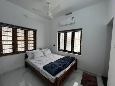 a bedroom with a bed in a room with windows at Happy Villa Homestay - 4 in Chelakara