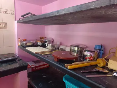 a kitchen with pink walls and a counter with pots and pans at Shivalaya Stays - Coimbatore in Coimbatore
