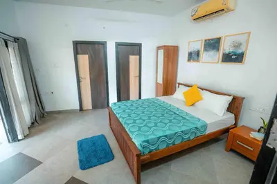 a bedroom with a bed with a blue comforter at Cabana by Grha - Charming Cottage at Kappad Beach in Kozhikode