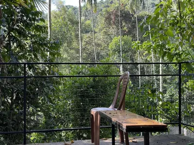 a wooden chair sitting on top of a balcony at Wetlands Wayanad Pool Resort with Natural Waterfalls in Padinjarathara