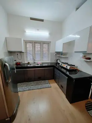 a kitchen with white cabinets and a black counter top at Aanandam - An Independent Villa in 1 Acre Farm in Wayanad