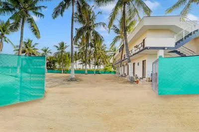 a house on the beach with palm trees at Super Hotel O Avinashi Road Coimbatore in Coimbatore