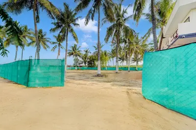 a green fence on a beach with palm trees at Super Hotel O Avinashi Road Coimbatore in Coimbatore