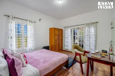 a bedroom with a bed and a desk and windows at StayVista at Orion's Crest ooty including breakfast in Ooty