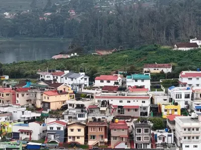 a group of houses on a hill next to a body of water at OOTY STAY AWHILE in Ooty