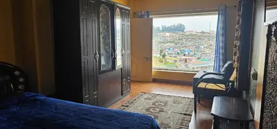 a bedroom with a door with a view of a city at OOTY STAY AWHILE in Ooty