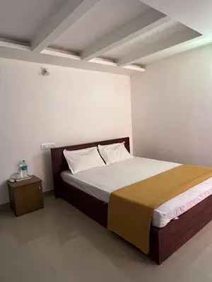 a bedroom with a bed and a night stand at Plaza Residency in Badagara
