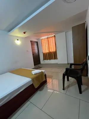 a bedroom with a bed and a chair and a window at Plaza Residency in Badagara