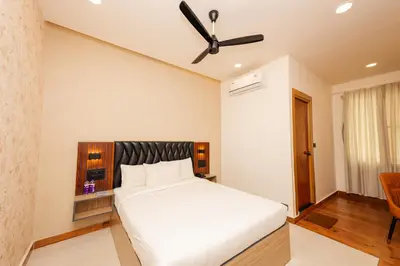 a bedroom with a white bed and a ceiling fan at THE CONTINENTAL INN & SUITES in Mysore