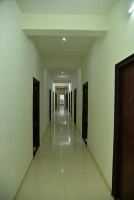 a hallway with white walls and a long hallway with black doors at ARIVU LODGE AC in Anaimalai