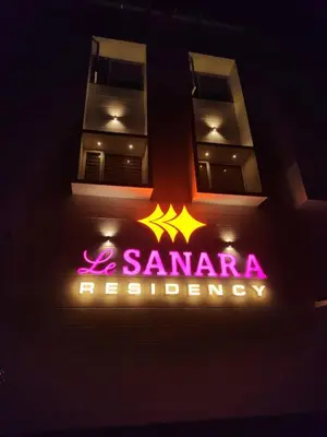 a building with a neon sign in the dark at Le Sanara Residency in Thanniyam