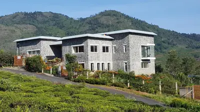 a large stone house on a hill with a garden at green home in Coonoor