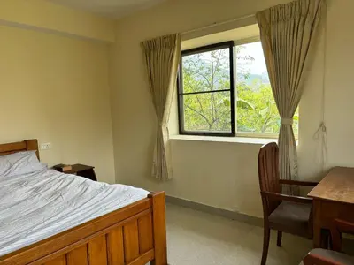 a bedroom with a bed and a desk and a window at green home in Coonoor