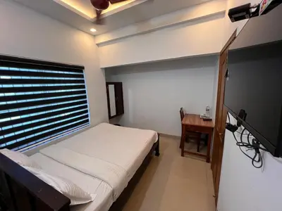 a bedroom with a bed and a television and a table at Confident Residency in Guruvāyūr