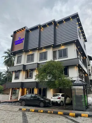 a building with two cars parked in front of it at Confident Residency in Guruvāyūr