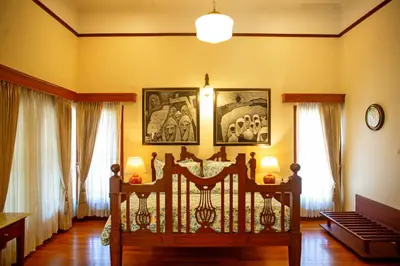a bedroom with a bed and paintings on the wall at Marlihill Bungalow - A CGH Earth SAHA Experience in Ooty