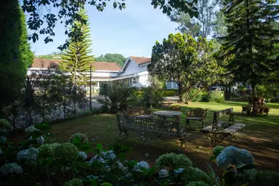 a garden with a bench and a table in the yard at Marlihill Bungalow - A CGH Earth SAHA Experience in Ooty