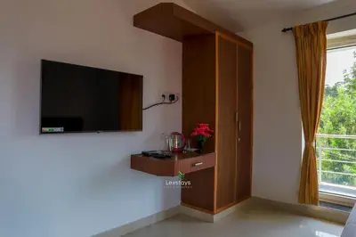 a living room with a flat screen tv on a wall at Green Premium Villa Ooty by Lexstays in Ooty