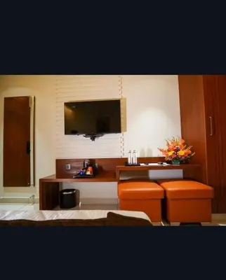 a room with two orange stools and a flat screen tv at Hotel Harigovindas Express Mysore in Mysore