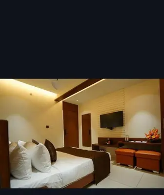 a hotel room with a bed and a living room at Hotel Harigovindas Express Mysore in Mysore