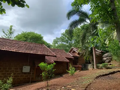 a group of houses with a palm tree in the background at Shantam Homestay - Powered by Grackle in Cheruthuruthi