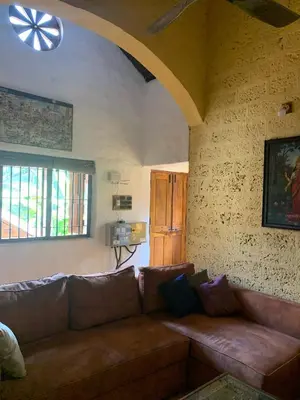 a living room with a brown couch and two windows at Shantam Homestay - Powered by Grackle in Cheruthuruthi