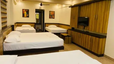 a hotel room with two beds and a television at POOJA inn in Guruvāyūr