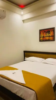 a bedroom with a large white bed with a painting on the wall at POOJA inn in Guruvāyūr