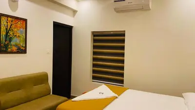 a bedroom with a bed and a chair and a window at POOJA inn in Guruvāyūr