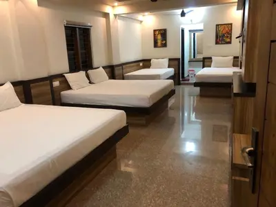 a room with three beds and a couch at POOJA inn in Guruvāyūr