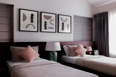two beds in a room with pictures on the wall at Nilgiri Valley Villa Ooty - a VKation Experience in Ooty