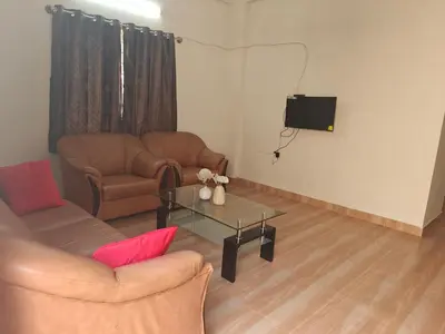a living room with two chairs and a table and a tv at Urban Nest Residence in Mysore