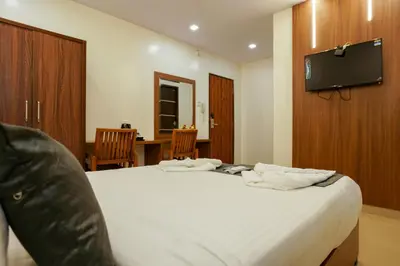 a bedroom with a large white bed with a flat screen tv at Royal Plaza City in Kozhikode
