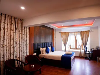 a bedroom with a bed and a table and a window at Vista Sunrise Resort Ooty Dodabetta in Ooty