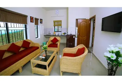 a living room with a couch and chairs and a table at Vrindhavan Mist City Resorts in Kanthalloor