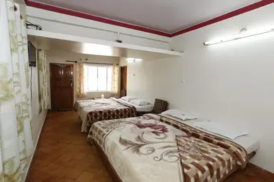 a room with three beds and a window at Hotel Sri Balaji in Ooty