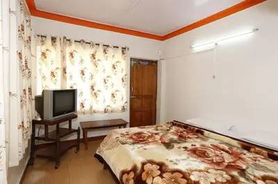 a bedroom with a bed and a tv in it at Hotel Sri Balaji in Ooty