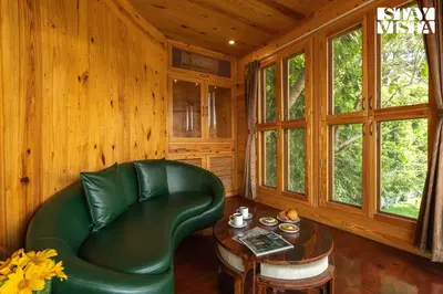 a living room with a green leather chair and a table at StayVista at Exotica Kabini - All Meals Included - Riverfront Villa in Antarasante