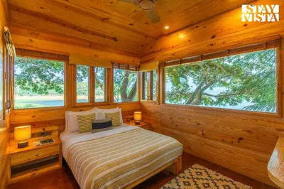 a bedroom with a bed in a log cabin at StayVista at Exotica Kabini - All Meals Included - Riverfront Villa in Antarasante