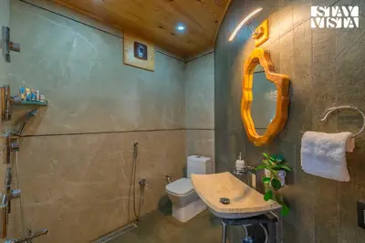 a bathroom with a sink and a toilet and a mirror at StayVista at Exotica Kabini - All Meals Included - Riverfront Villa in Antarasante