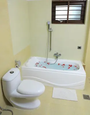 a bathroom with a toilet and a bath tub at Jal Mahal Resort and Spa in Mysore