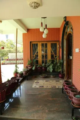 a lobby with chairs and plants in a building at Madhu Manish Homestay and Rooms in Coonoor