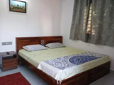 a bedroom with a bed with a wooden frame and a window at Vigneshwara Nilaya in Mysore