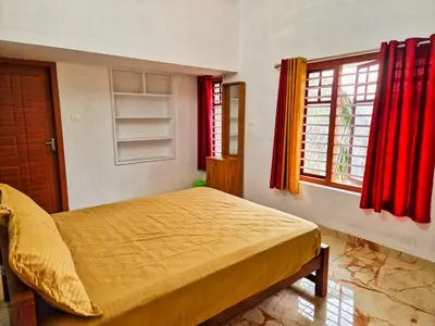 a bedroom with a bed and windows with red curtains at Centre Home Homestay Wayanad in Kalpetta