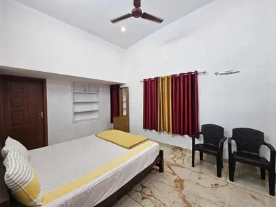 a bedroom with a bed and two chairs at Centre Home Homestay Wayanad in Kalpetta