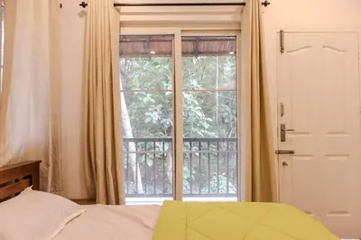 a bedroom with a bed and a large window at Peechi Green Valley in Pattikad