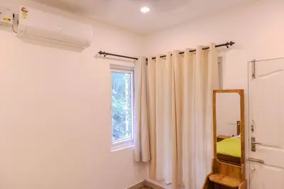 a bedroom with a window and a mirror and a mirror at Peechi Green Valley in Pattikad